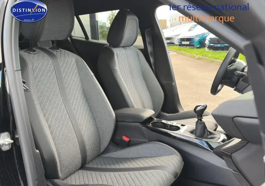 Vue intérieure côté conducteur du Peugeot 2008 noir 2025, mettant en valeur les sièges tissu gris et la boîte manuelle.