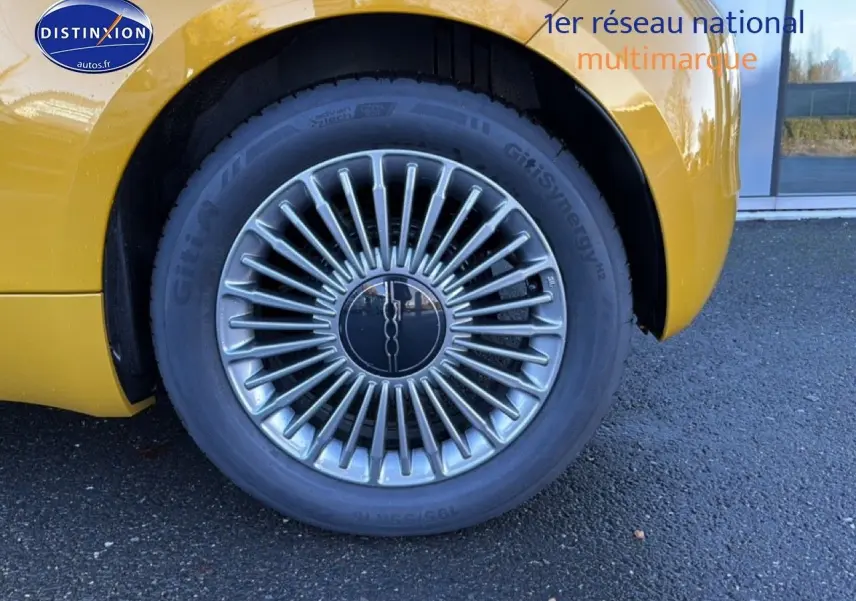 Gros plan sur la roue arrière droite d'une FIAT 500 Yellow Gold Métal avec jante alu au design rayonné.