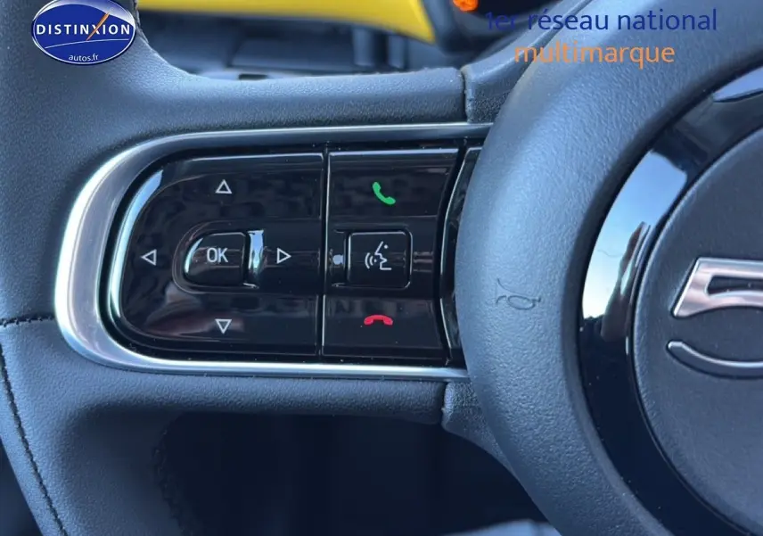 Gros plan sur les commandes au volant à gauche d'une FIAT 500 Yellow Gold Métal, avec boutons de téléphone et navigation.
