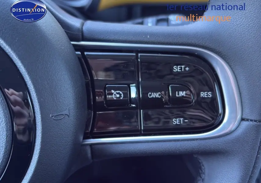 Gros plan sur les commandes multifonctions du volant côté gauche d'une Fiat 500 Yellow Gold Métal hybride 2026.