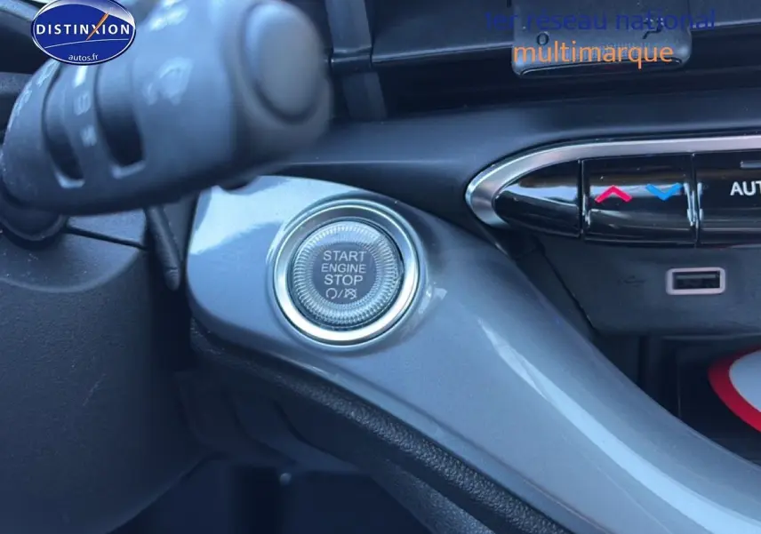 Détail intérieur du bouton Start Engine Stop sur la console grise d'une FIAT 500 hybride Yellow Gold Métal.