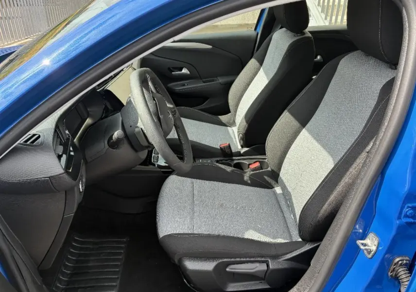 Vue intérieure côté conducteur de l’Opel Corsa 2025 bleu voltaik, montrant les sièges tissu bicolore et le volant.