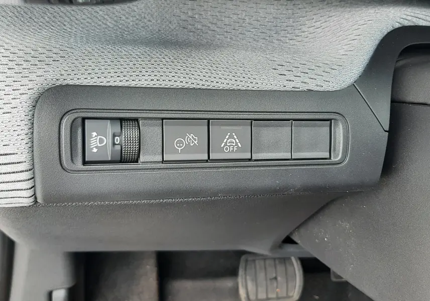 Gros plan sur les commandes de réglage des phares et aides à la conduite côté gauche du tableau de bord d'un Citroën C3 Aircross gris Mercury.