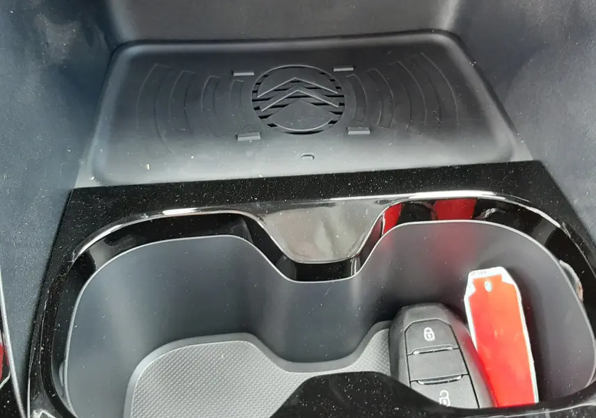 Gros plan sur le porte-gobelets intérieur noir du Citroën C3 Aircross avec tapis de rangement et clé de voiture.