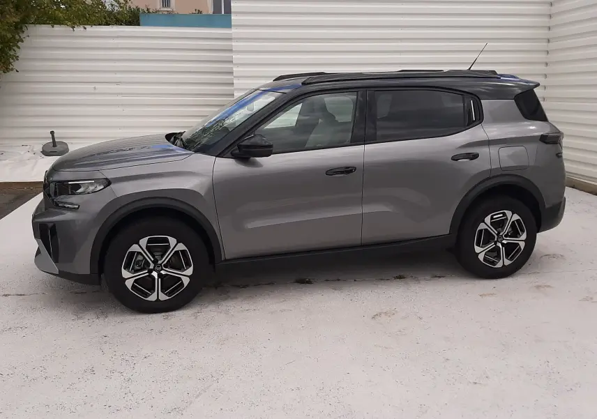 Vue de profil côté gauche du Citroën C3 Aircross gris Mercury avec toit noir et jantes bi-ton, stationné sur sol clair.