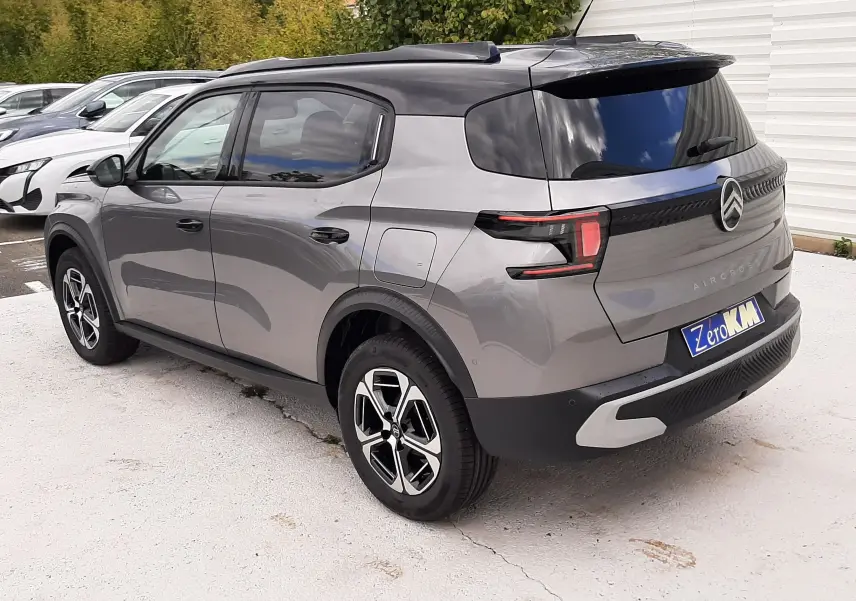 Vue 3/4 arrière droite d'un Citroën C3 Aircross gris Mercury avec toit noir et jantes bi-ton, stationné en extérieur.