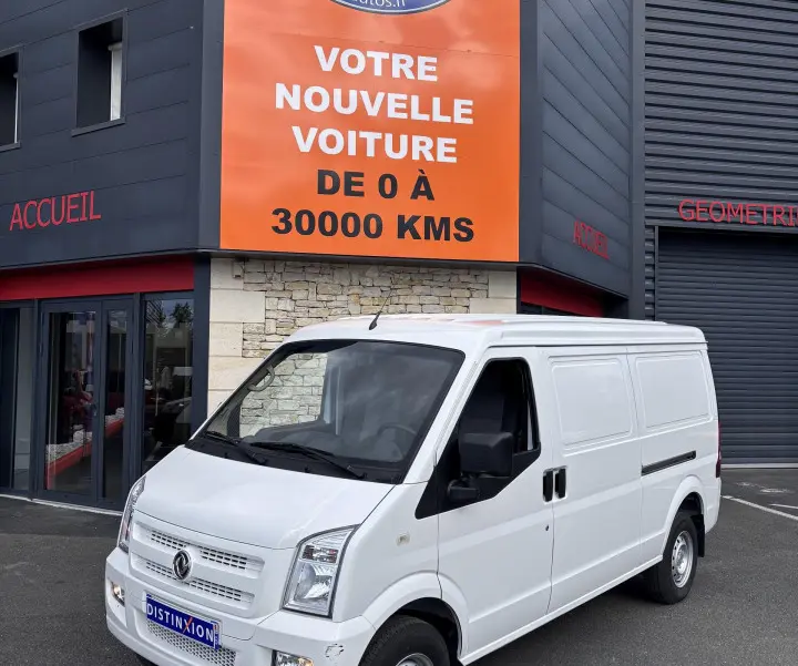Fourgon électrique DFSK EC35 blanc vu en 3/4 avant droit devant un bâtiment avec enseigne orange Distinxion.