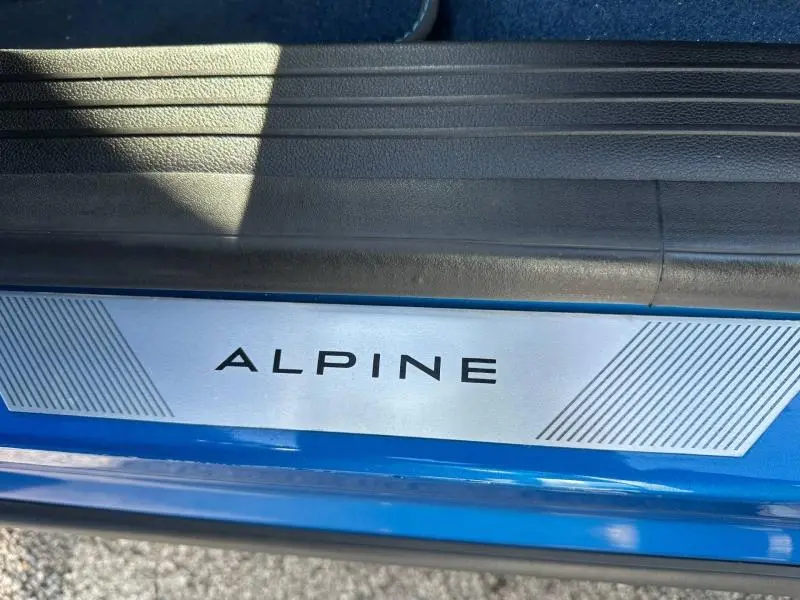 Gros plan sur la plaque de seuil de porte "ALPINE" sur la carrosserie bleu sommet métallisé du Renault Rafale 2025.