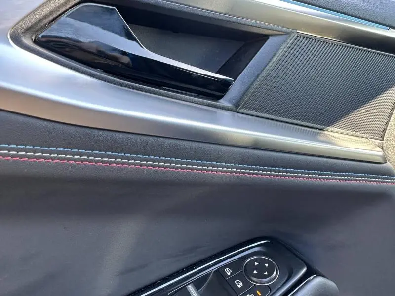 Détail de la portière avant gauche du Renault Rafale bleu avec surpiqûres tricolores et commandes électriques.