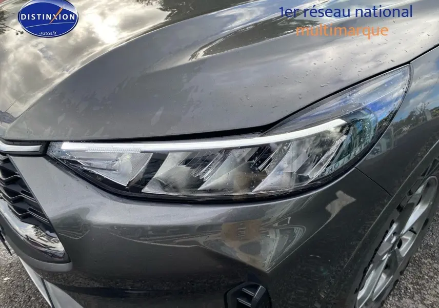 Gros plan sur le phare avant droit du Ford Kuga 2025 gris Magnetic Fashion métallisé avec jante alu visible.