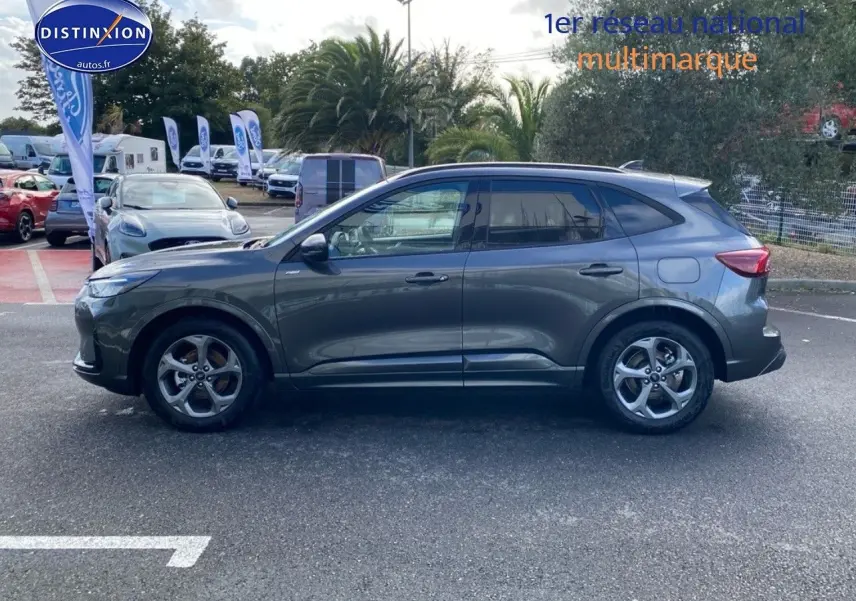 Ford Kuga 2025 gris Magnetic Fashion métallisé en vue de profil côté gauche sur parking extérieur.