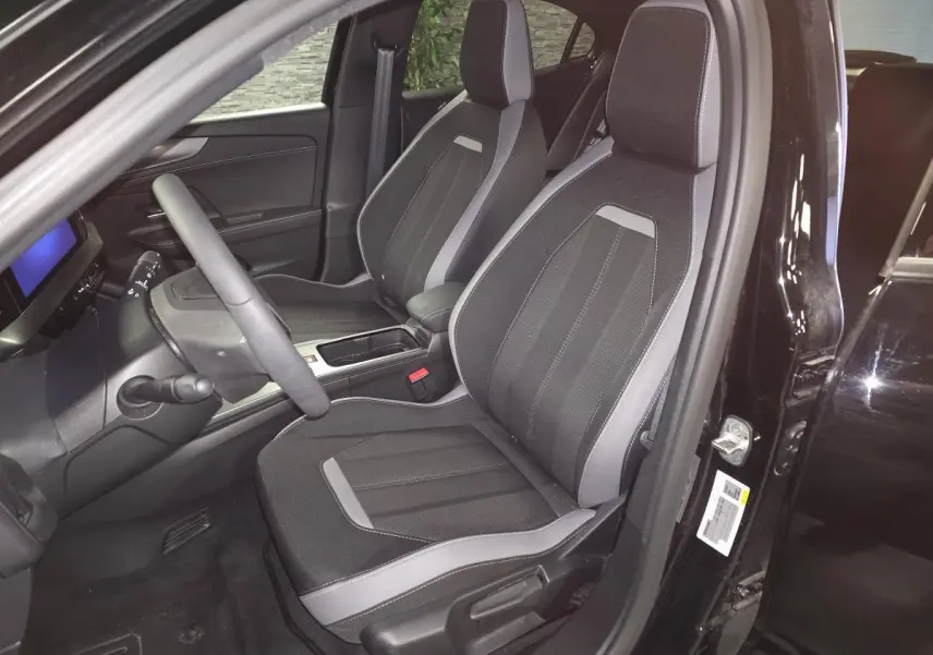 Intérieur avant droit de l'Opel Mokka-e noir 2025, sièges tissu noir et gris avec console centrale visible.