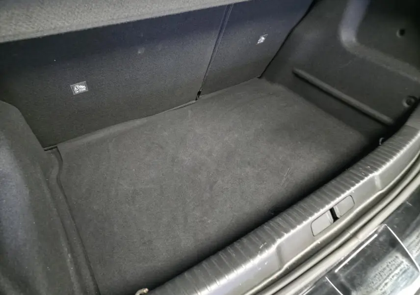 Coffre vide en vue plongeante d'un Opel Mokka-e noir, montrant la moquette noire et les fixations Isofix arrière.