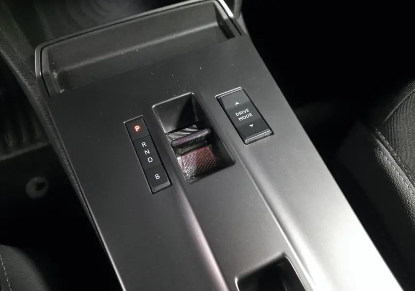 Gros plan sur la console centrale noire de l’Opel Mokka-e 2025, avec sélecteur de boîte automatique et bouton Drive Mode.