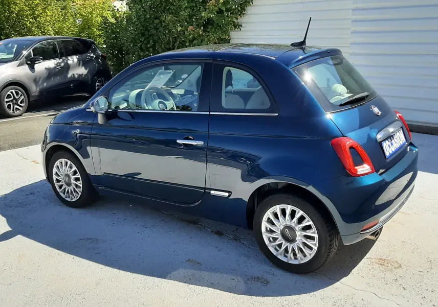 Vue 3/4 arrière droite d'une FIAT 500 Lounge bleu profond avec jantes alliage et antenne de toit noire.