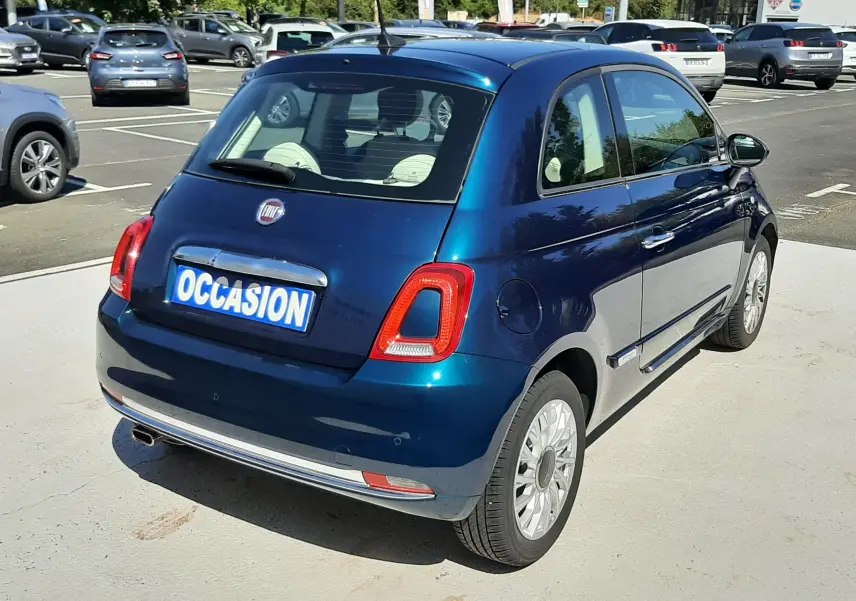 Vue 3/4 arrière droite d'une FIAT 500 Lounge 2018 bleu métallisé avec feux arrière LED et jantes alliage en parking.