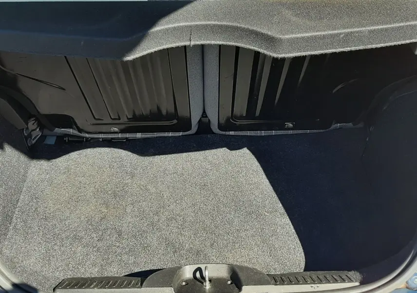 Coffre ouvert vu de l'arrière d'une FIAT 500 bleu 2018, montrant l'espace de chargement et le dossier des sièges arrière beige.