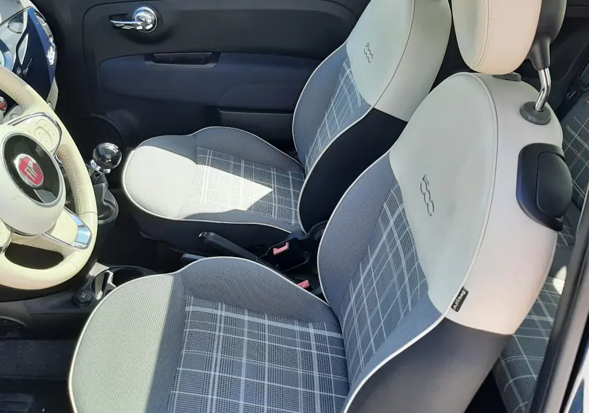 Vue intérieure côté gauche de la FIAT 500 Lounge 2018, sièges avant gris à motif à carreaux et volant beige.