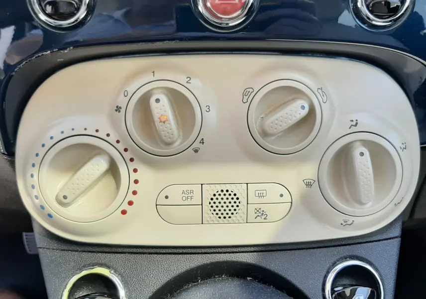 Tableau de bord beige et bleu de Fiat 500 1.2 8V 69 Lounge 2018, avec commandes de climatisation et bouton de danger.