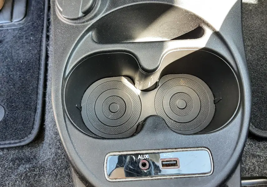 Gros plan sur la console centrale noire de la Fiat 500 bleu, montrant porte-gobelets, prise 12V, port AUX et USB.