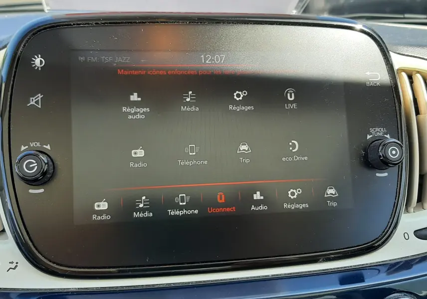 Vue rapprochée de l’écran tactile central d’une Fiat 500 bleue de 2018 avec commandes multimédia et tableau de bord beige.