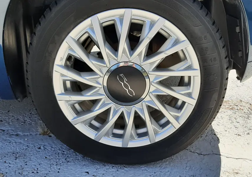 Gros plan sur la jante argentée d'une FIAT 500 bleu, mettant en valeur le logo central distinctif.