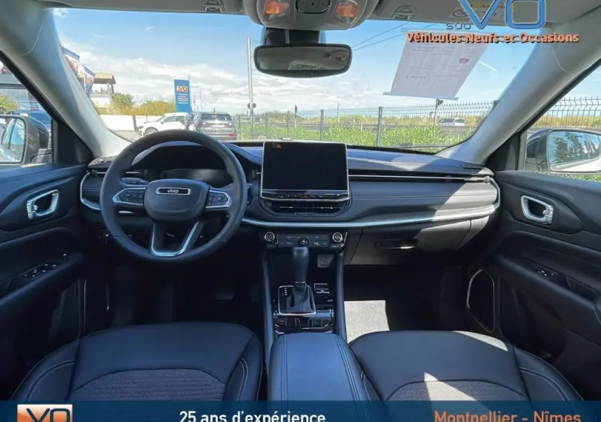 Intérieur du Jeep Compass 2024 blanc, vue avant du tableau de bord avec écran tactile et volant multifonction.