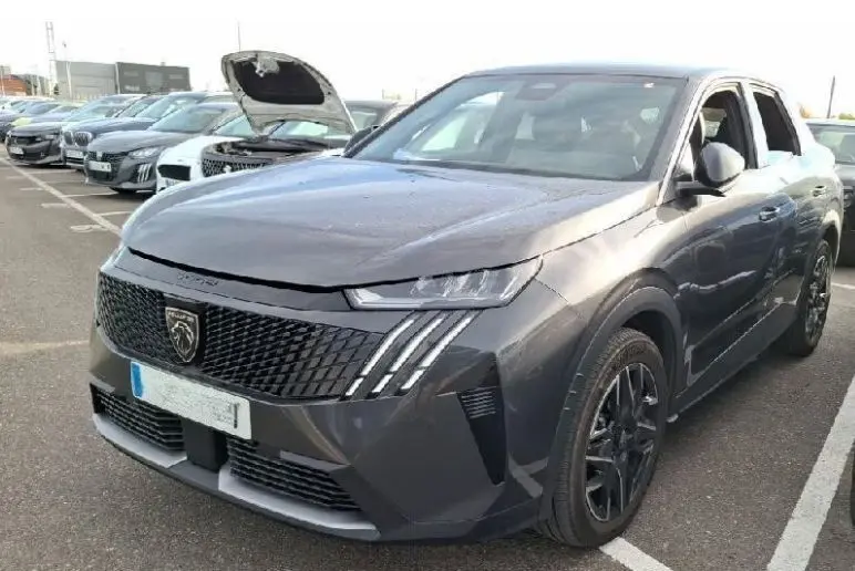 Vue 3/4 avant droite d’un Peugeot 3008 gris 2025 avec calandre noire et feux LED distinctifs en griffes.