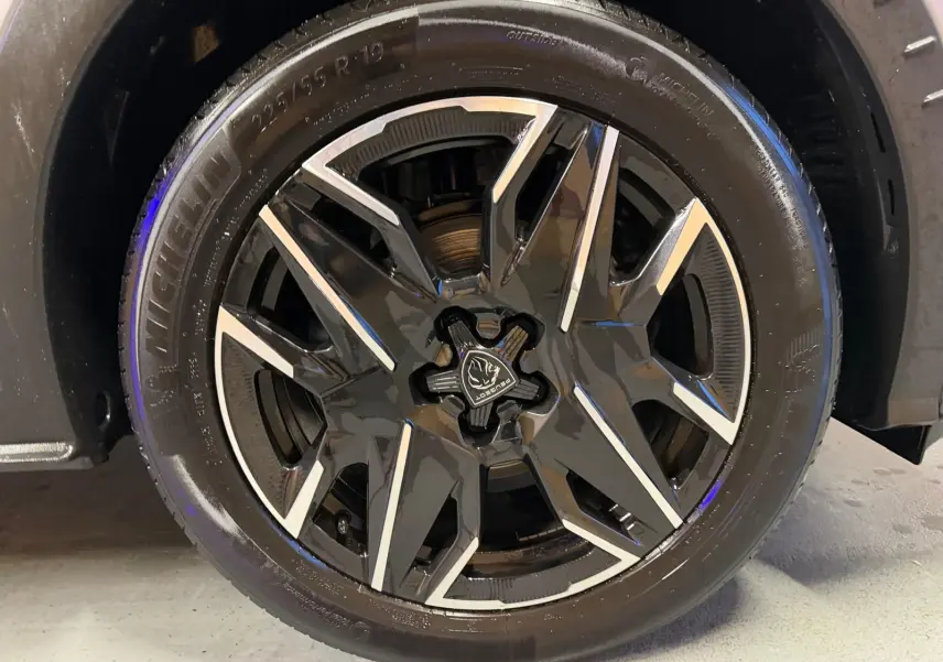 Gros plan sur la jante noire et argentée du Peugeot 3008 gris 1.2 HYBRID 136 ALLURE, roue avant droite.