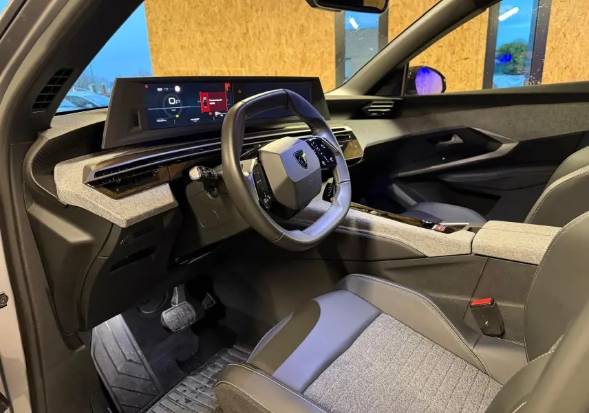 Vue intérieure côté conducteur du Peugeot 3008 gris 2025, mettant en valeur le volant compact et l'écran numérique large.