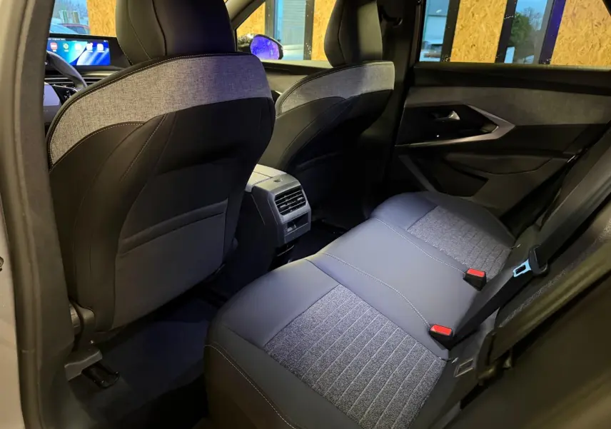Vue intérieure arrière droite du Peugeot 3008 1.2 Hybrid 136 Allure, sièges tissu noir et gris, ambiance moderne et lumineuse.
