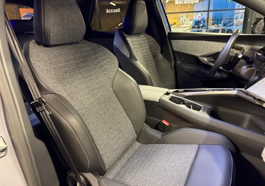 Vue intérieure côté droit du Peugeot 3008 1.2 HYBRID 136 Allure 2025, sièges tissu gris et cuir noir, console centrale visible.