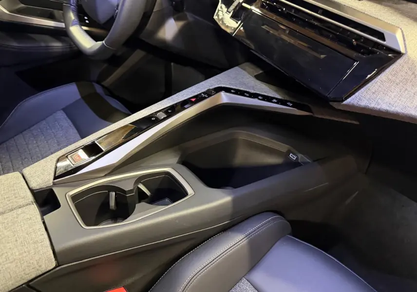 Vue intérieure côté passager du Peugeot 3008 1.2 Hybrid 136 Allure gris, avec console centrale et sièges tissu noir et gris.