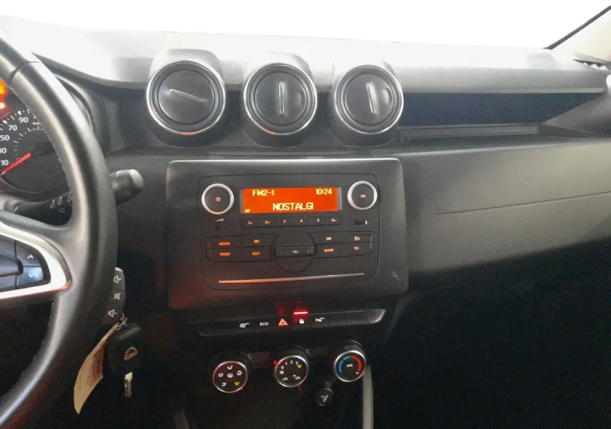 Vue rapprochée du tableau de bord du Dacia Duster 2021, montrant les commandes de climatisation et les boutons de fonction.
