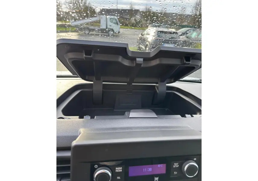 Vue intérieure sur le rangement ouvert au-dessus de la console centrale du Renault Trafic Fourgon gris clair, avec pare-brise gouttelette.