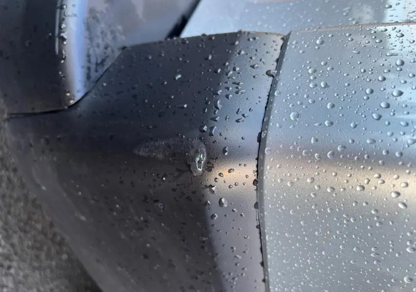 Gros plan sur l’arrière droit gris clair du Renault Trafic Fourgon avec gouttes de pluie visibles sur la carrosserie.