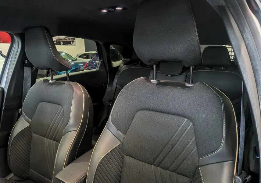 Vue intérieure rapprochée des sièges avant en tissu et cuir noir avec surpiqûres contrastantes dans une Renault Symbioz Gris Cassiopé.