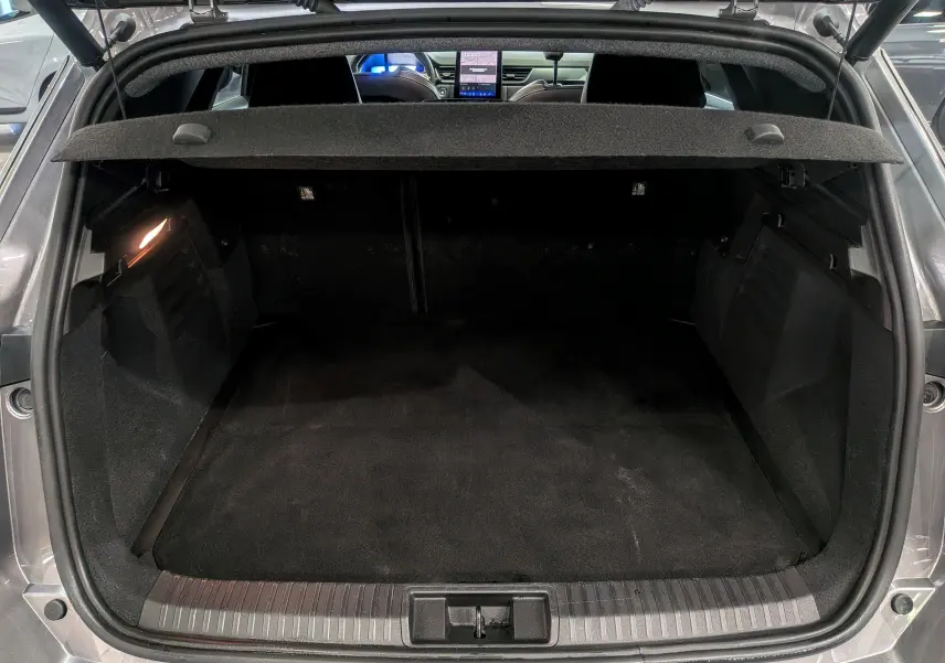 Coffre ouvert vu de l'arrière d'une Renault SYMBIOZ gris Cassiopé, avec intérieur noir et tablette arrière relevée.