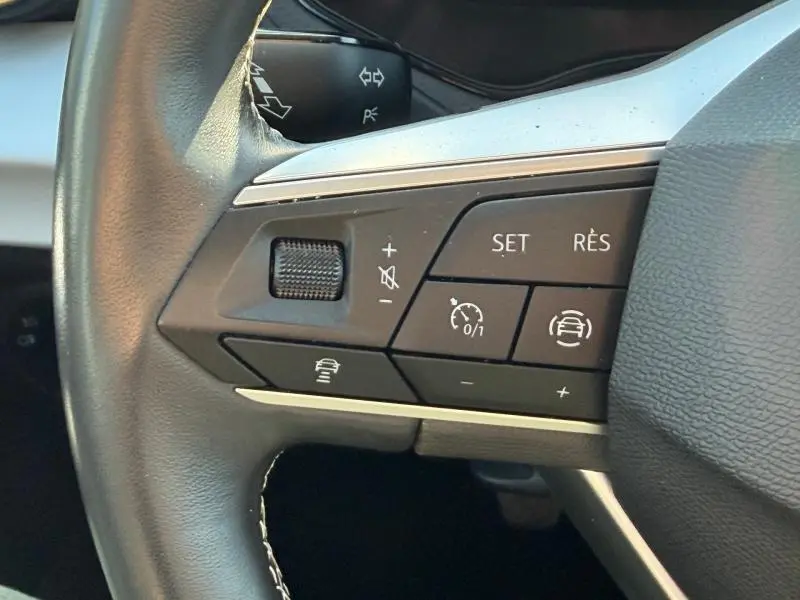 Gros plan sur les commandes multifonctions du volant cuir noir du SEAT Arona gris Magnétique Métal 2025.