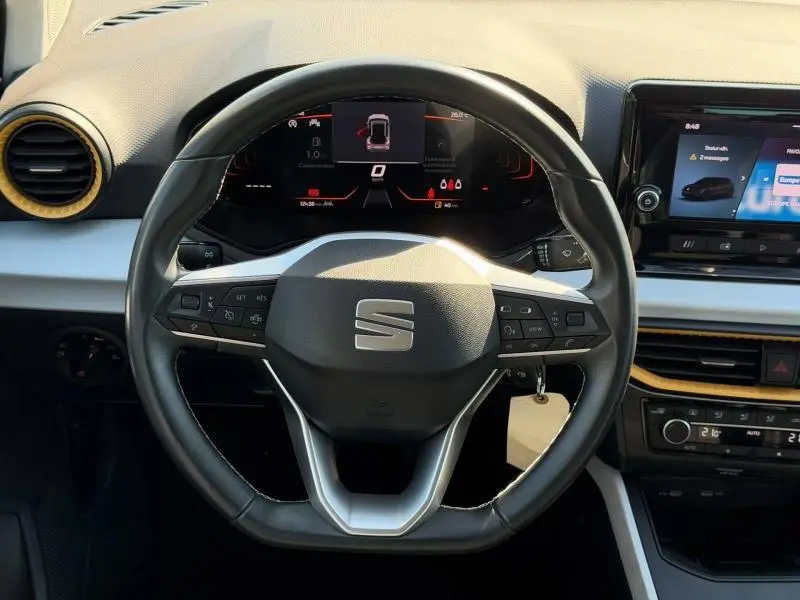 Vue rapprochée du volant cuir multifonction et du tableau de bord numérique du SEAT Arona 2025, ambiance intérieure gris et noir.