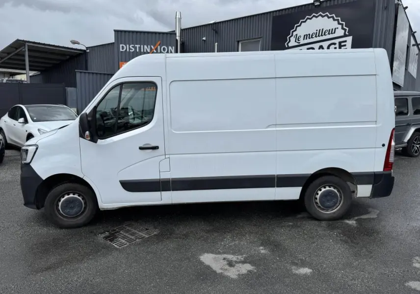 Profil côté gauche d'un utilitaire Renault Master blanc avec baguettes noires et roues tôlées 16 pouces, stationné en extérieur.
