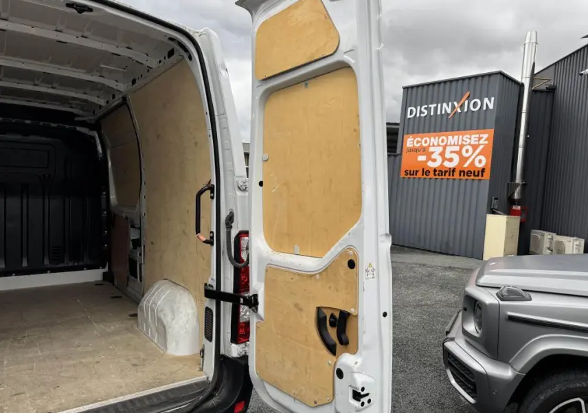 Vue arrière ouverte du Renault Master blanc montrant l'intérieur de la zone de chargement avec habillage bois et porte arrière tôlée.