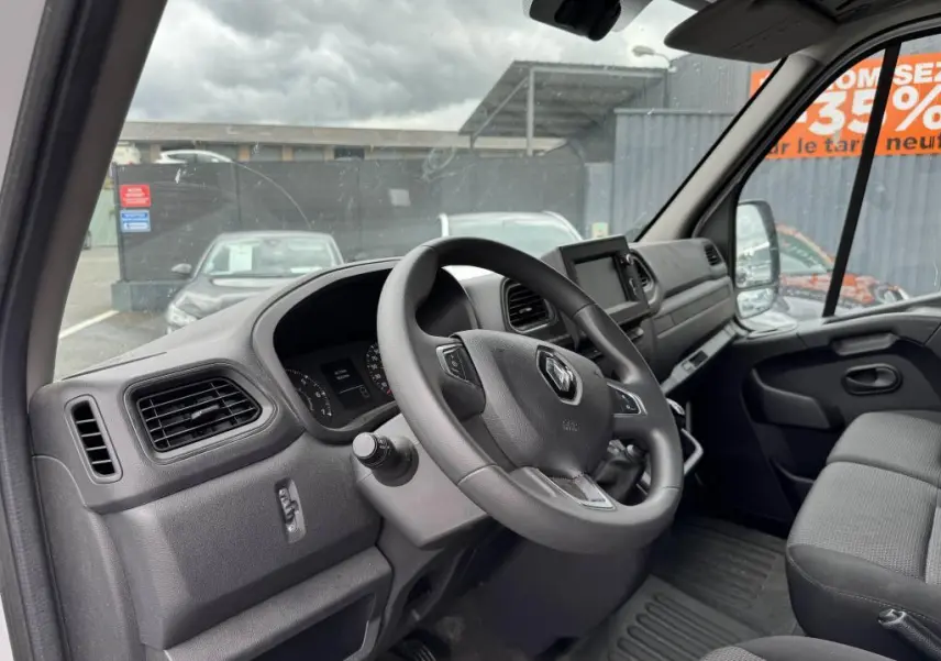 Vue intérieure côté conducteur du Renault Master blanc 2022, tableau de bord et volant avec logo Renault visibles.
