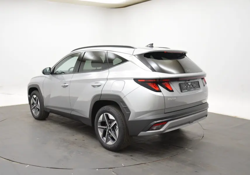 Vue 3/4 arrière droite du Hyundai Tucson 2025 hybride en gris Shimmering Silver avec jantes 18 pouces et vitres surteintées.