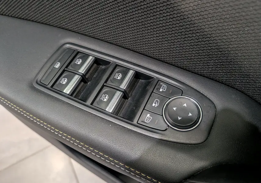 Gros plan sur les commandes des vitres et rétroviseurs côté conducteur du Renault Symbioz gris Cassiopé, finition Iconic.