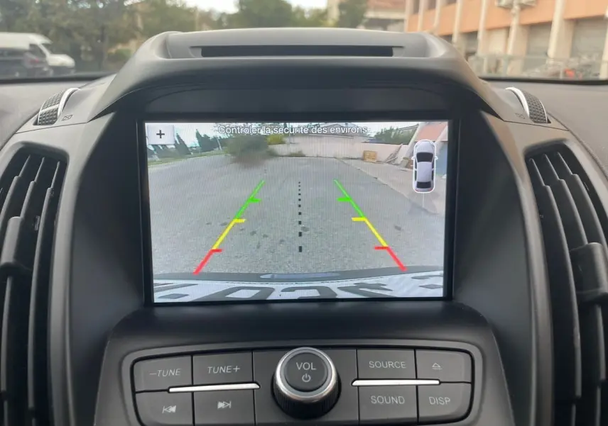 Écran de caméra de recul du Ford Kuga gris 2017, vue intérieure centrée sur le tableau de bord et les commandes audio.