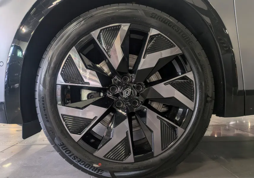 Gros plan sur la roue avant droite du Renault Rafale E-TECH gris schiste satin avec jante alliage bicolore et logo Renault central.