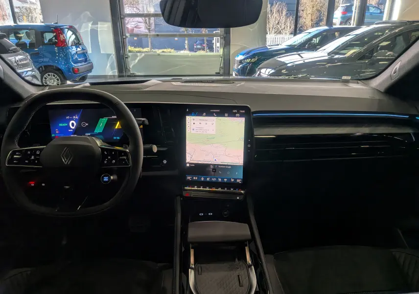 Vue intérieure frontale du tableau de bord du Renault Rafale E-TECH 2025, avec écran tactile vertical et éclairage d'ambiance bleu.