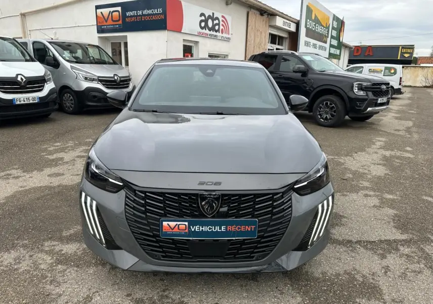 Vue de face d'une Peugeot 208 gris 2025 avec calandre noire et feux LED verticaux distinctifs, stationnée en extérieur.