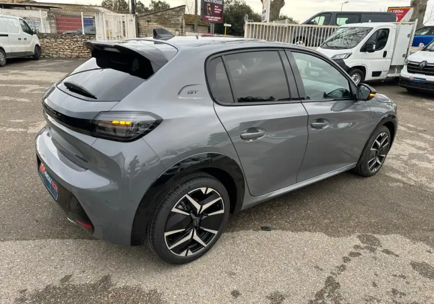 Vue 3/4 arrière droite d'une Peugeot 208 Hybrid 110 e-DCS6 GT gris avec jantes alliage 17 pouces et feux arrière allumés.